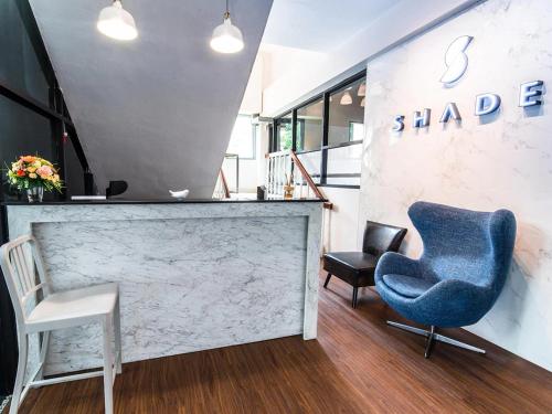 a lobby with a blue chair and two chairs at Shade House - Bitec Bangna in Bangkok