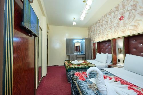 a hotel room with two beds and a flat screen tv at Quality Hotel Apartments in Sabkhah