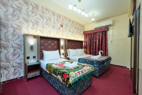 a hotel room with two beds and a television at Quality Hotel Apartments in Sabkhah