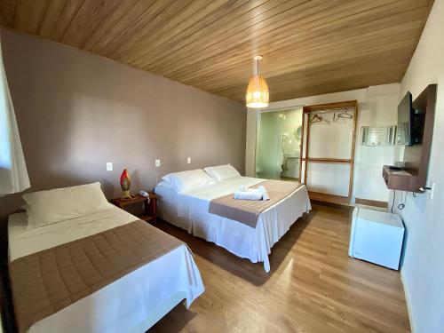 a hotel room with two beds and a tv at Pousada Yapara-Tyba in Japaratinga