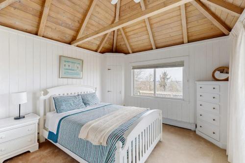 a white bedroom with a bed and a window at La Casa De La Playa in Gloucester