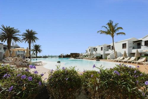 a swimming pool with palm trees and lounge chairs at R2 Bahia Kontiki in Puerto del Carmen