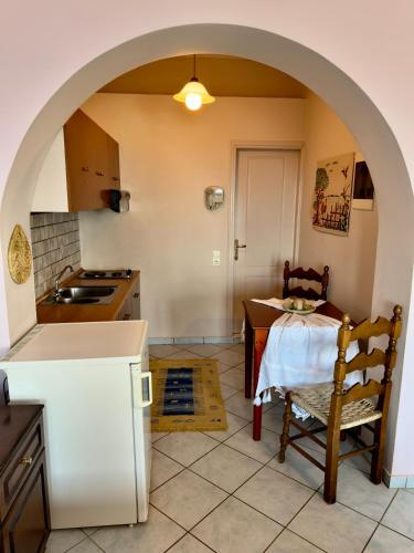 a kitchen with an archway and a table and chair at Natasa studios Kythera in Kythira