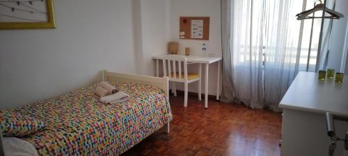 a small bedroom with a bed and a desk at Vieiras House Quarto Solteiro in Barreiro