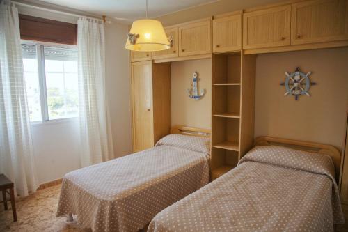 two twin beds in a room with a window at Apartamentos Avenida Areas II in Sanxenxo