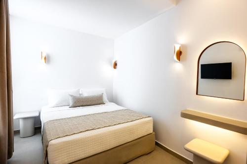 a small bedroom with a bed and a mirror at Caldera Jewel Santorini in Firostefani