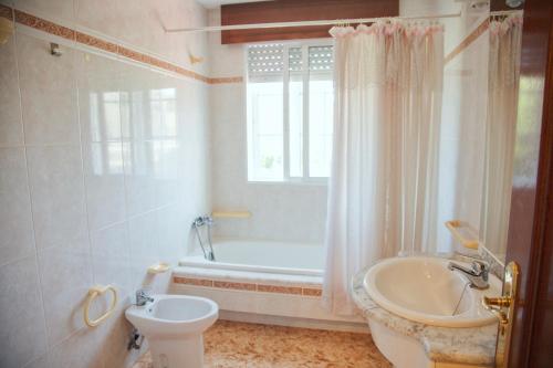 a bathroom with a tub and a toilet and a sink at Apartamentos Avenida Areas II in Sanxenxo