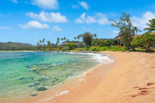 a beach with blue water and palm trees at Beachfront Lae Nani 3BD Condo AC & Heated Pool in Kapaa