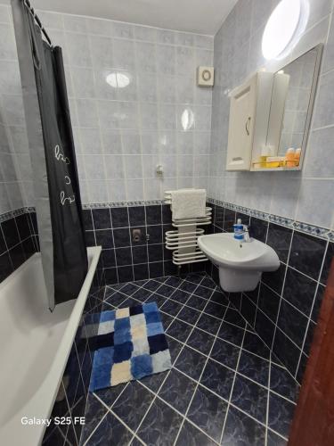 a blue tiled bathroom with a sink and a toilet at Zafir Luxory in Kaposvár