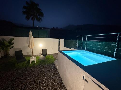 a swimming pool at night with two chairs and an umbrella at Casa Hoya de Carta in Candelaria