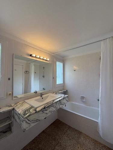 a bathroom with a sink and a tub and a mirror at Villa Bouganvilla Parking privado 32 en la playa in Tossa de Mar