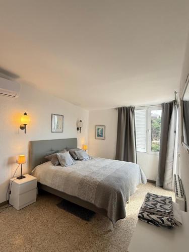 a white bedroom with a bed and a window at Villa Bouganvilla Parking privado 32 en la playa in Tossa de Mar