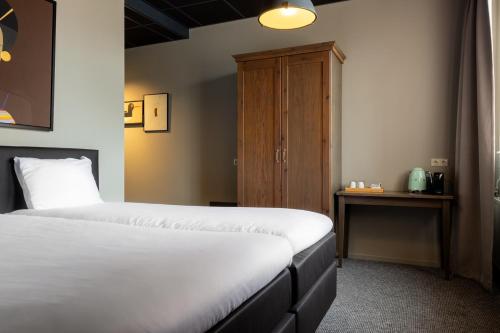 a bedroom with two beds and a wooden cabinet at Logementen Dokkum in Dokkum