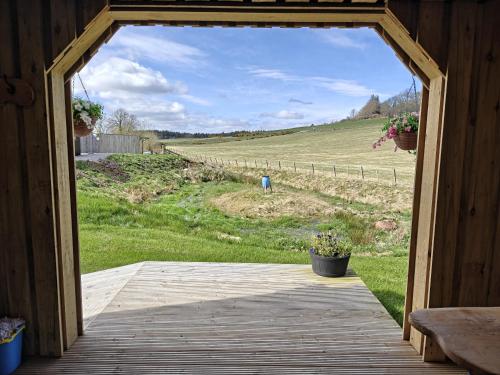 a door to a cabin with a view of a field at Pleasant Point Holiday Cottages in Glenurguhart