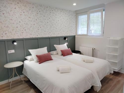 a bedroom with a large white bed with two pillows at El Pinar Beach in Comillas