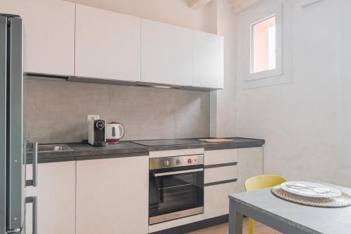 a kitchen with white cabinets and a stove and a table at LaVero Maison in Castelfranco Emilia