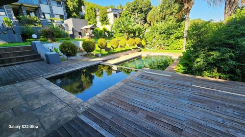 a swimming pool in a garden with a wooden deck at The Mansion Lodge in Hartbeespoort