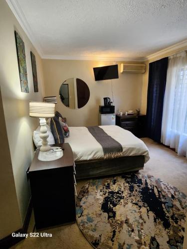 a hotel room with a bed and a table with a lamp at The Mansion Lodge in Hartbeespoort