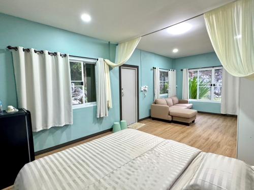 a bedroom with blue walls and a bed and a couch at นพรัตน์การ์เด้นฮิลล์ in Uthai Thani
