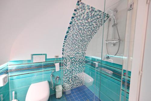 a bathroom with a blue tiled shower and a toilet at Beach House Ischia - Seafront & Aragonese Castle View - in Ischia Town