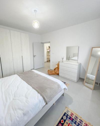 a white bedroom with a large bed and a mirror at Modern Air Conditioned 2BR in Heart of Shkodër in Shkodër