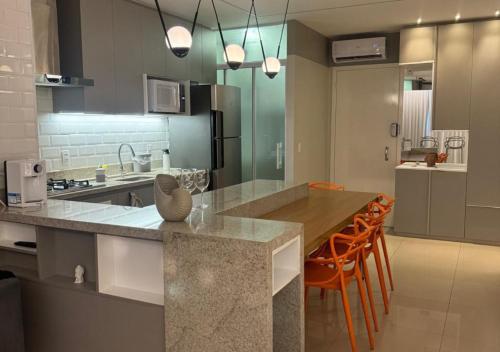 a kitchen with a table and some orange chairs at Metropolitan Sidney in Goiânia