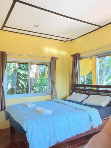 a bedroom with a large bed and two windows at Elephant garden2 in Trat