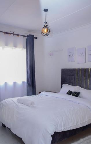 a bedroom with a large white bed with a window at Meg Cozy Homes Executive 1Bedroom and 2Bedroom Apartments Near Rupa Mall The Noble Hotel & Poa Place Resort in Eldoret