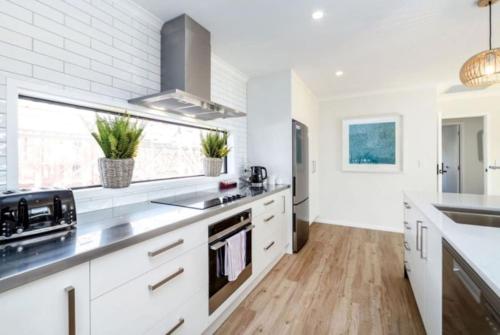 a kitchen with white cabinets and wood floors at Arthurs Vineyard - Sleeps 10 in Martinborough