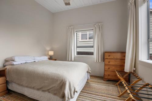 a white bedroom with a bed and a window at Claras Togs and Towels in Waihi Beach
