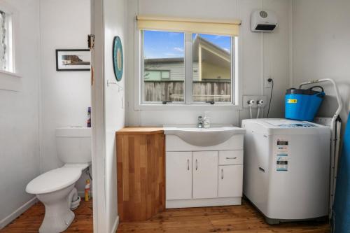 a bathroom with a toilet and a sink and a window at Claras Togs and Towels in Waihi Beach
