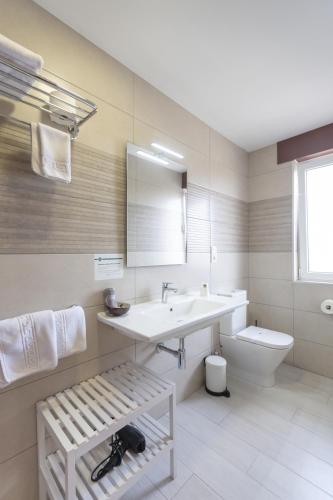 a white bathroom with a sink and a toilet at Hotel Ros Mary in Ribadeo