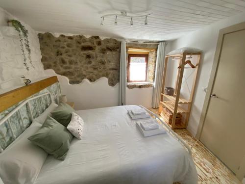 a bedroom with a large white bed with a stone wall at La Casuca ONE De Lebeña in Lebena