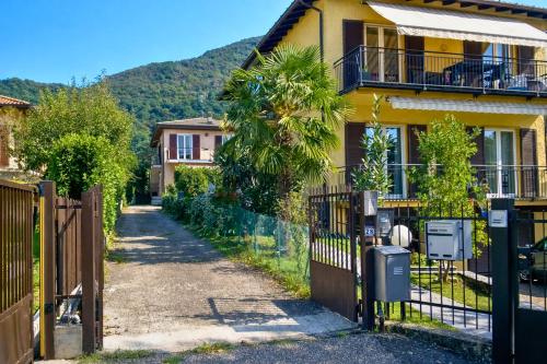 a house with a fence and a palm tree at Casa Mariarosa in Maccagno Inferiore