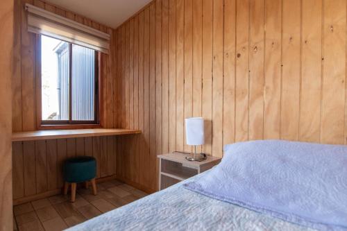 a bedroom with a bed with a lamp and a window at Cabañas Rosner in Valdivia