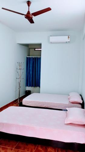 three beds in a room with a ceiling fan at Thomson Kylas Rooms in Ettumānūr