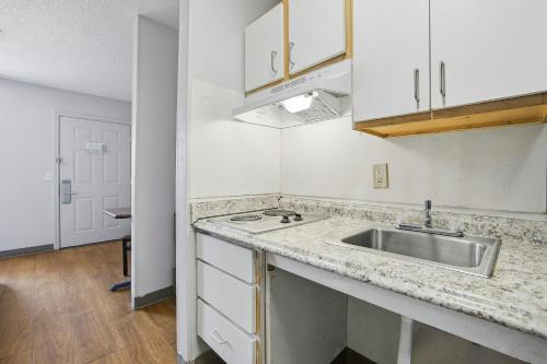 a kitchen with a sink and a counter top at HomeTowne Studios by Red Roof Atlanta - Peachtree Corners in Norcross