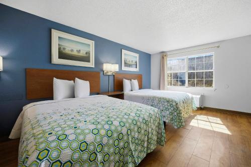 a hotel room with two beds and a window at HomeTowne Studios by Red Roof Atlanta - Peachtree Corners in Norcross