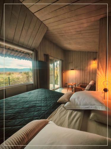 a bedroom with a large bed with a large window at La Pause En Soi - Cabanes climatisées avec Jaccuzi privatif en option in Ponlat-Taillebourg