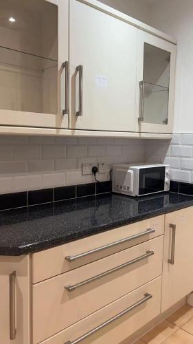 a kitchen with white cabinets and a microwave on a counter at PLUS Properties Oxford 3 in Stoke on Trent