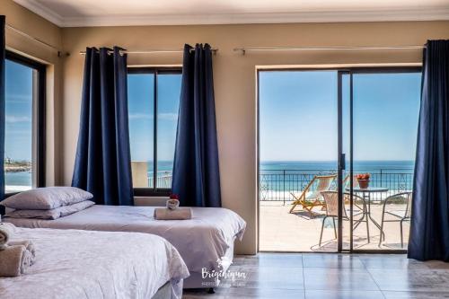 two beds in a bedroom with a view of the ocean at Boardwalk in Britannia Bay