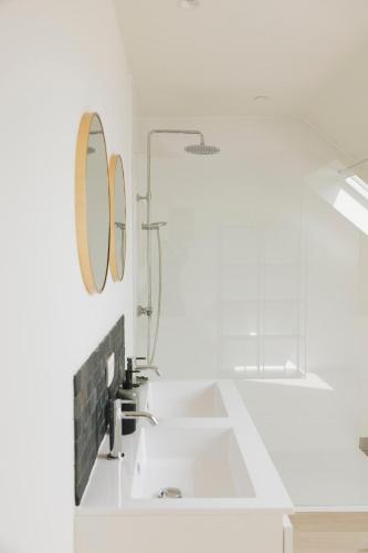 a white bathroom with a sink and a mirror at Vakantiewoning 't Veld in Ledegem