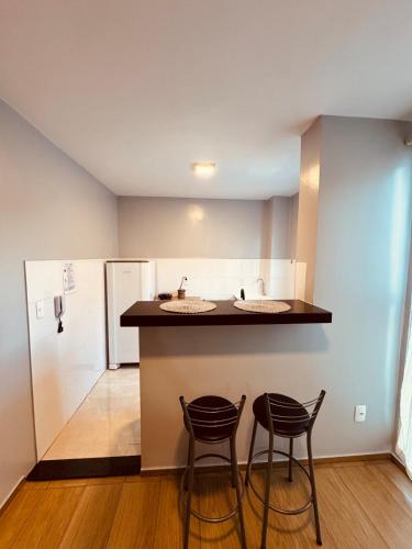 a kitchen with two stools and a counter with two sinks at Apt 404 BL 6 entrada de londrina in Cambé