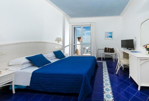 a hotel room with a blue bed and a desk at Hotel Club Due Torri in Maiori