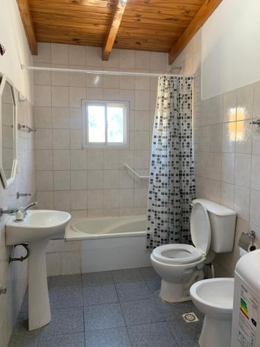 a bathroom with a tub and a toilet and a sink at Apart Cerezos in Los Antiguos