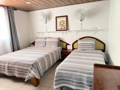 two beds sitting next to each other in a room at Tropical Bliss Pool Wi-Fi BBQ Near Quepos Manuel Antonio in Quepos