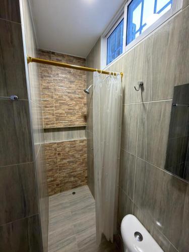 a bathroom with a shower and a toilet and a window at HOSTAL CARACOLI - HUECO in Valledupar