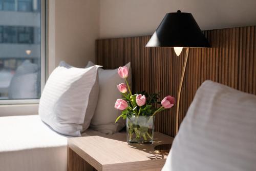 a vase of pink flowers on a table next to a bed at Hotel Terrado Lyon in Santiago
