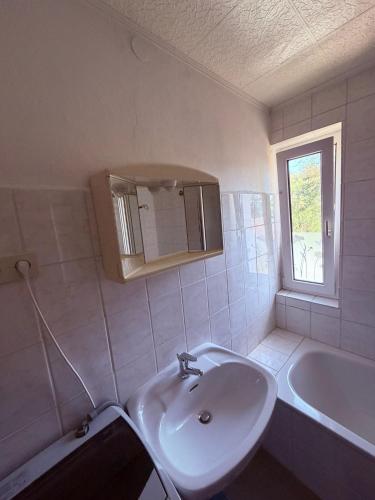 a white bathroom with a sink and a tub at Gästehaus Nachtigall in Gädheim