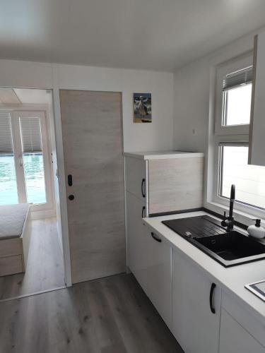 a white kitchen with a sink and a door at Hausboot Santa Lucia Novigrad - Floating Sea House in Novigrad Istria